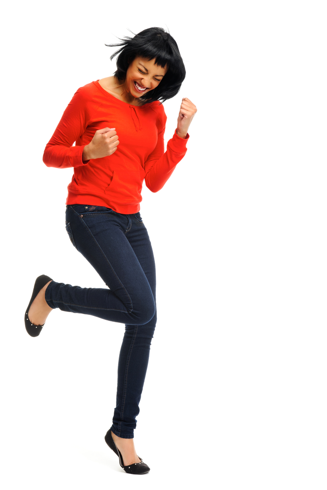 Happy woman celebrates by cheering and dancing in studio, isolated on white